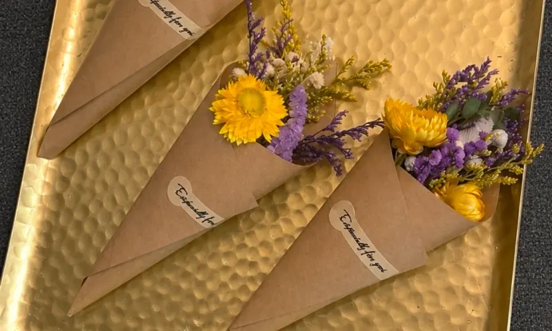 Small wrapped floral gifts on a gold tray