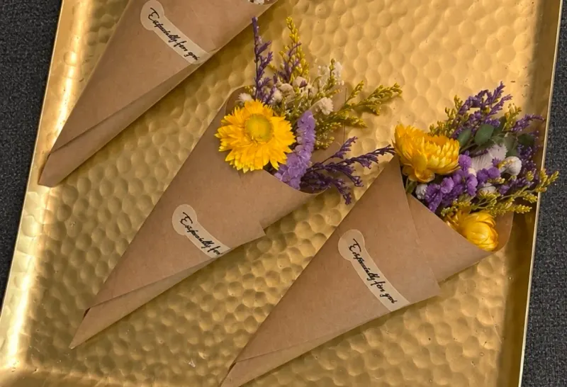Small wrapped floral gifts arranged on a gold tray